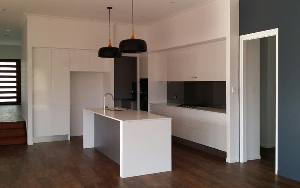 Kitchen With Wooden Flooring and White Cabinets — Wilkinson Homes Pty Ltd in Annandale, QLD